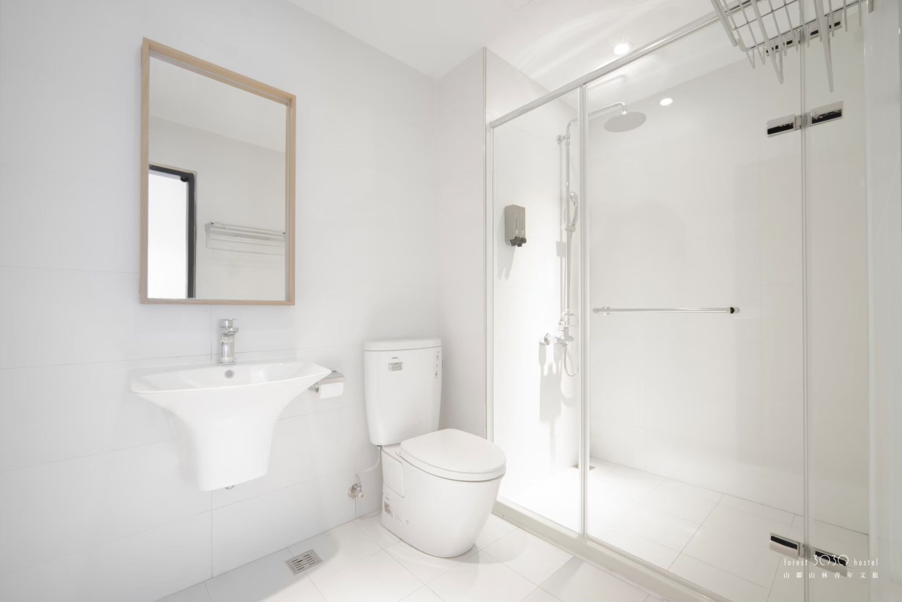 Un baño moderno con lavamanos, inodoro y ducha con mampara de vidrio.