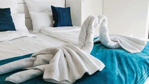 Una habitació d'hotel amb dos llits, cadascun amb roba de llit blanca i almoades blaves.
