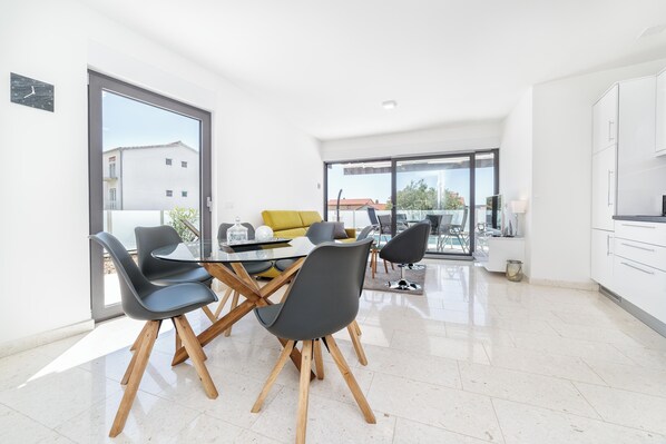 Un espace repas moderne avec une table en verre, des chaises noires et un canapé jaune.