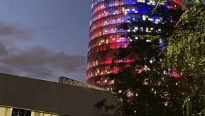 Ein hohes, zylindrisches Gebäude mit einer reflektierenden Fassade, umgeben von Bäumen.