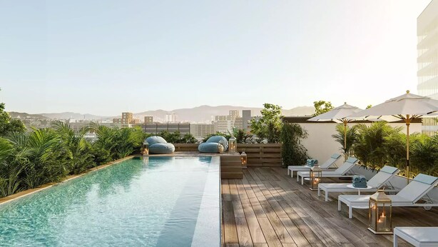 Ein Pool auf dem Dach mit Liegestühlen und Blick auf die Stadt.