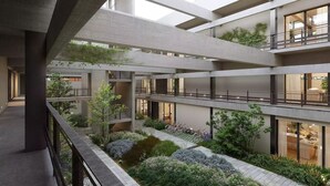 Ein mehrgeschossiges Atrium mit einem zentralen Garten, Balkonen und Blick auf die Innenräume.