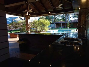 A modern kitchen with a large island, a built-in sink, and a view of a pool and outdoor area.