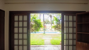 A room with a view of a garden through a wooden door with glass panels.