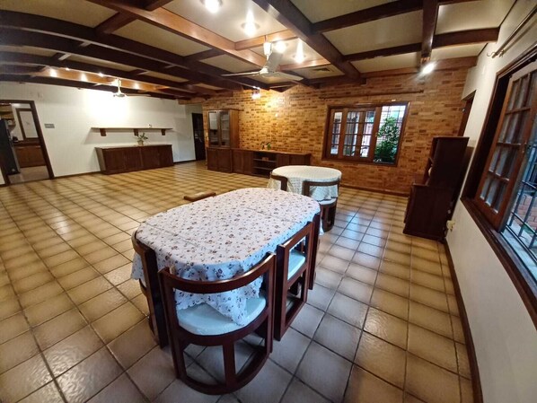 A spacious kitchen with a large dining table and chairs, a brick wall, and a window with a view.