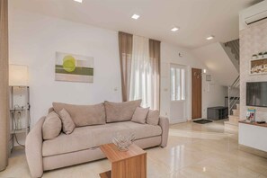 A modern living room with a sofa, a coffee table, and a painting on the wall. - Holiday home with three bedrooms (Malinska)