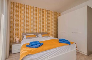 Une chambre d’hôtel avec un lit, une table de chevet avec une lampe, une armoire et un mur décoré d’un motif.