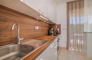 Une cuisine moderne avec un revêtement mural en bois, un évier en acier inoxydable et des appareils électroménagers intégrés.