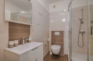 A modern bathroom with a shower, toilet, and sink.