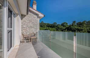 A balcony with a stone wall, a glass fence, and a seating area with two chairs. - Holiday home with three bedrooms (Malinska)