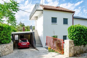 Simple, functional home surrounded by lush greenery and a secure red metal gate.