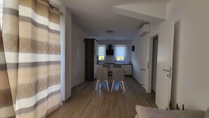 Ein modernes Wohnzimmer mit einer Couch, einem Essbereich mit Stühlen und einer Küche im Hintergrund.