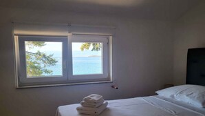 Ein Schlafzimmer mit Bett, einem Fenster mit Meerblick und einem Stapel Handtüchern auf dem Bett.
