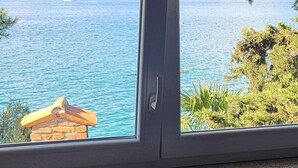 Ein Fenster mit Blick auf ein Gewässer und etwas Grün.