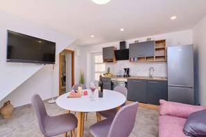 A modern kitchen with a TV, dining table, and chairs. - Holiday apartment with two bedrooms in a quiet location (Nerezine)