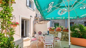 En terrasse med et bord, stole, en parasol og krukkeplanter.
