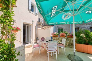 A patio with a table and chairs, an umbrella, and potted plants. - Holiday apartment with two bedrooms in a quiet location (Nerezine)