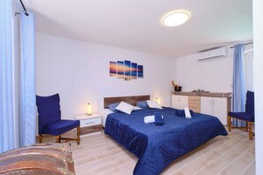A bedroom with a bed, two bedside tables, a nightstand, a chair, a bench, a wall-mounted air conditioner, and a ceiling light. - Holiday apartment with two bedrooms in a quiet location (Nerezine)