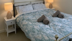 Een slaapkamer met een bed, twee nachtkastjes en drie ingelijste foto’s aan de muur.