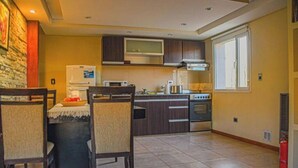 Une cuisine moderne avec des meubles de rangement en bois foncé, un four à micro-ondes encastré et une cuisinière à gaz.