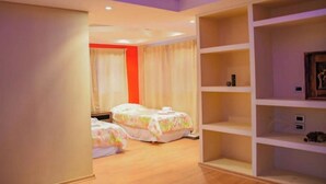 Une chambre d’hôtel avec deux lits, une grande étagère et une fenêtre avec des rideaux.