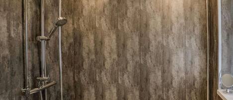 Un baño con bañera, ducha con múltiples cabezales y espejo instalado en la pared.
