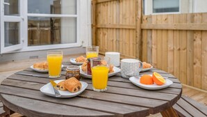 A wooden table set with breakfast items including croissants, orange juice, and a mug.