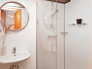 Ein Badezimmer mit Duschkabine, Waschbecken und Spiegel.