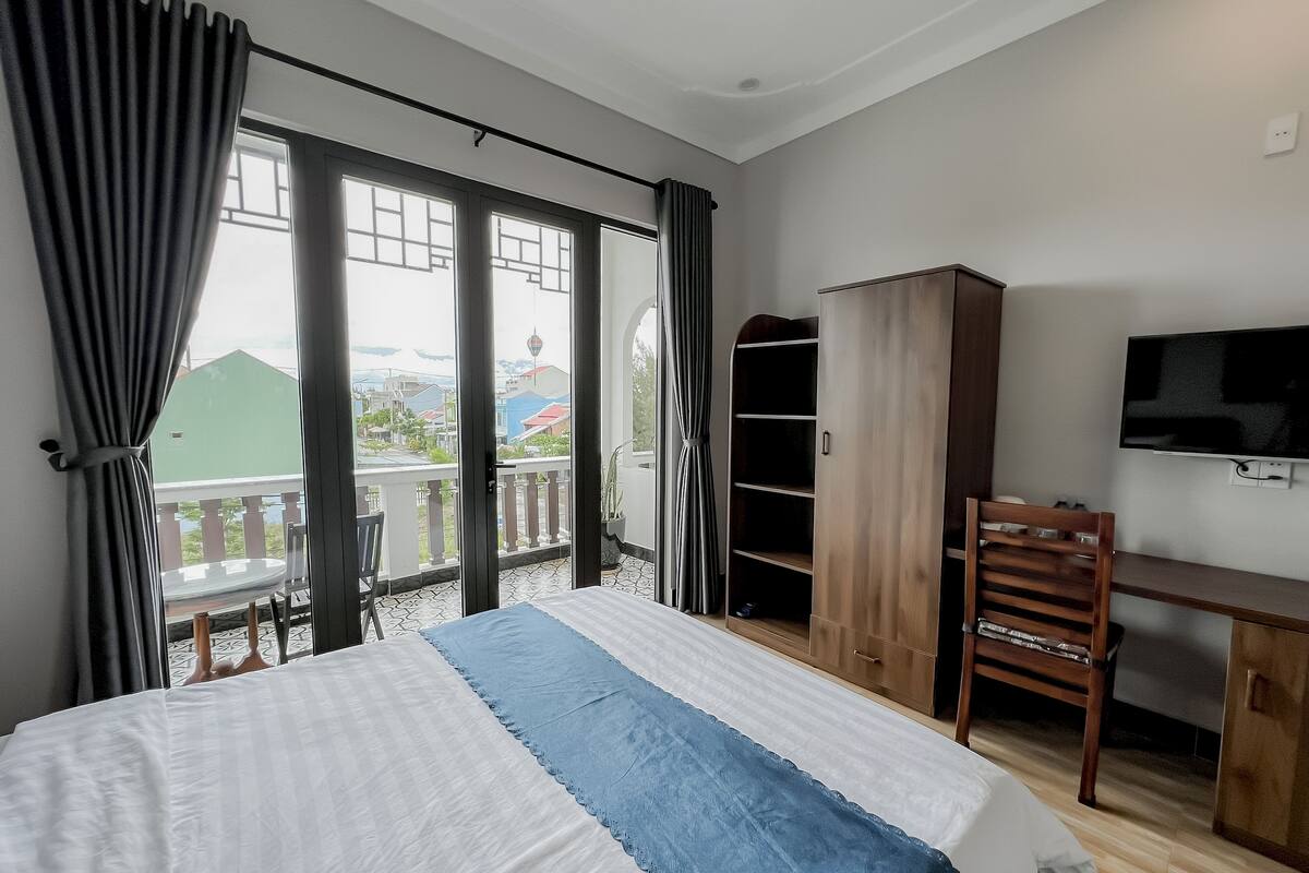 A bedroom with a bed, a desk, a wardrobe, and a TV.