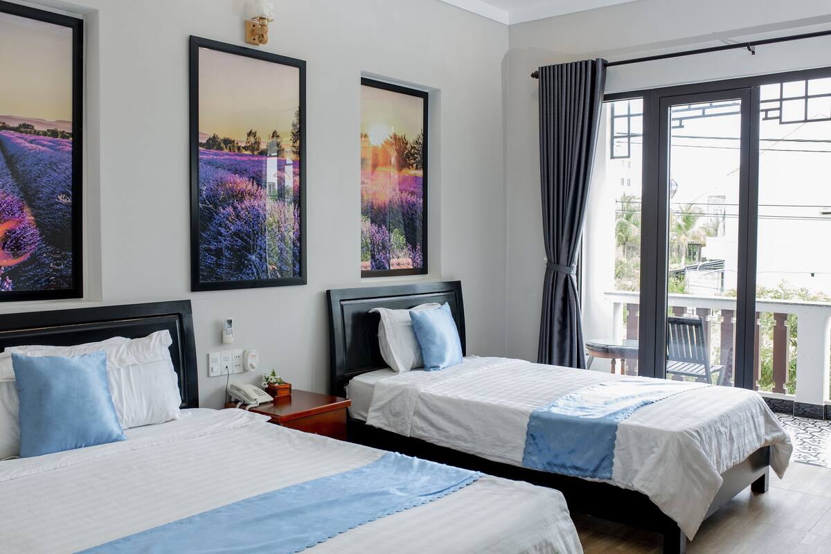 A hotel room with two beds, a balcony with a view, and artwork on the walls.