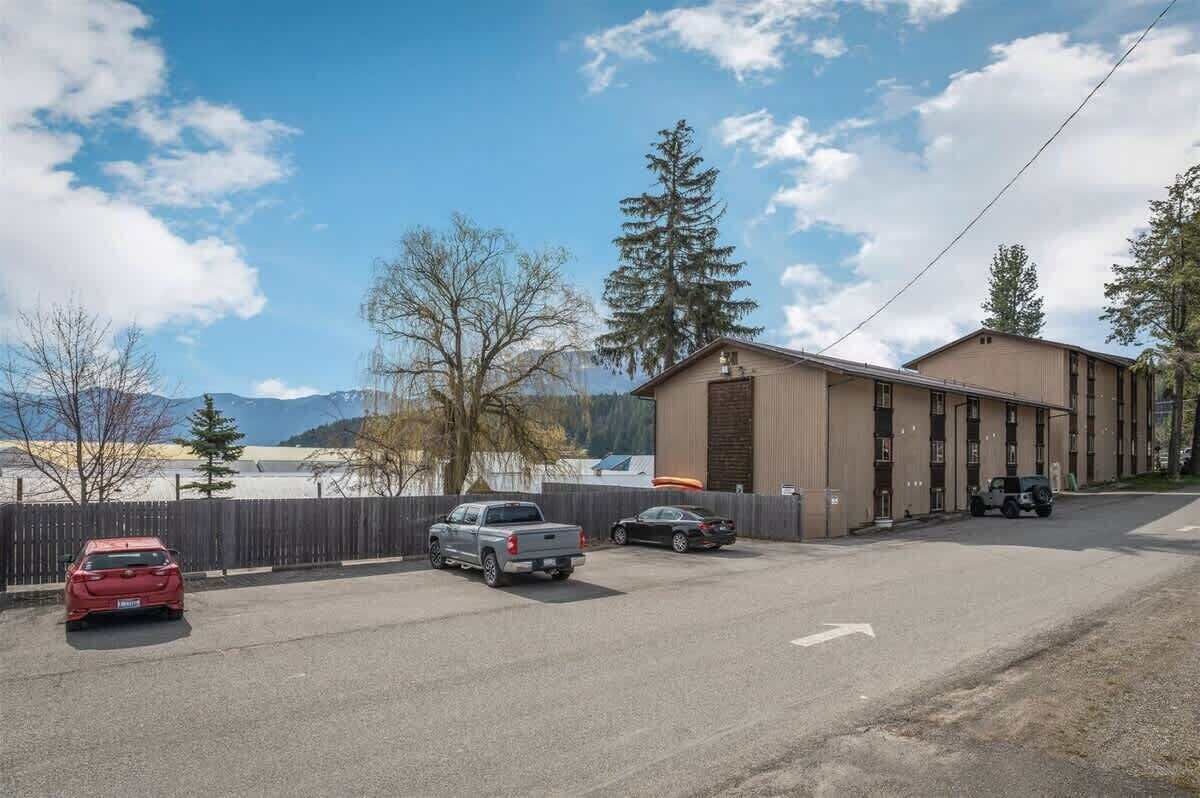 A building with a flat roof and a large garage door, surrounded by a parking lot with several cars.