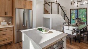 A modern kitchen with wooden cabinets, a stainless steel refrigerator, and a dining area with a table and chairs. - Dover Bay Luxe Home w/ Private Hot Tub - Sleeps 12 (Dover)