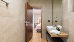 A modern bathroom with a wooden door, a large mirror, and a vanity with a sink and towel rack. - Villa Ana Skicini in Jursici (Jursici)