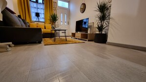 A modern living room with a sofa, a coffee table, a TV, and potted plants. - Cosy Stay in Stoke on Trent By Villazu (Stoke-on-Trent)
