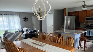 Ein Essbereich mit Holztisch und Stühlen, einer Deckenleuchte und einer Küche im Hintergrund.
