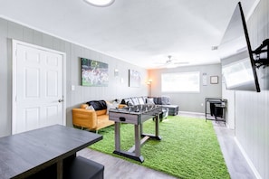 Ein Zimmer mit einem Kicker, einer Couch, einem Couchtisch und einem Fernseher.