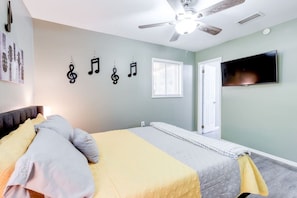 Ein Schlafzimmer mit einem Bett, einem Deckenventilator, einem Fernseher und einer Wand mit Noten.