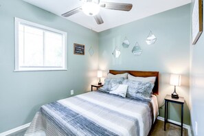 Ein Schlafzimmer mit einem Bett, zwei Nachttischen, einem Deckenventilator und dekorativen Wandspiegeln.