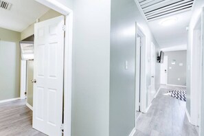 A hallway with a white door, a ceiling vent, and a checkered rug. - Walking distance to USM_Heart of Hattiesburg! (Hattiesburg)