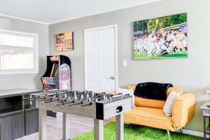 A room with a foosball table, a sofa, a door, and a framed sports picture. - Walking distance to USM_Heart of Hattiesburg! (Hattiesburg)