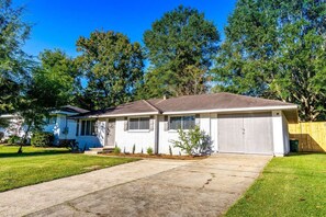 A single-story house with a front garage, a driveway, and a well-maintained lawn. - Walking distance to USM_Heart of Hattiesburg! (Hattiesburg)