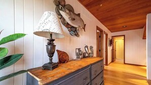 Un plafond en bois, une sculpture de poisson fixée au mur, une lampe et une commode à tiroirs.