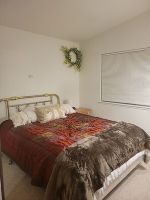 Cozy retreat with a single bed, nightstand, and lamp, set against a serene backdrop.