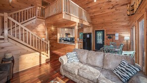 Ein Interieur einer Holzhütte mit einer Holztreppe, einer Couch und einem Essbereich.