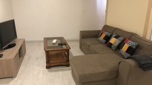 Een woonkamer met een bank, een salontafel en een televisie op een dressoir.
