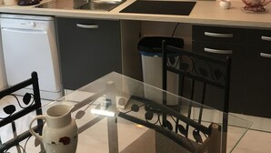 Een kleine keuken met een vaatwasser, een koffiezetapparaat, een spoelbak en een vuilnisbak.