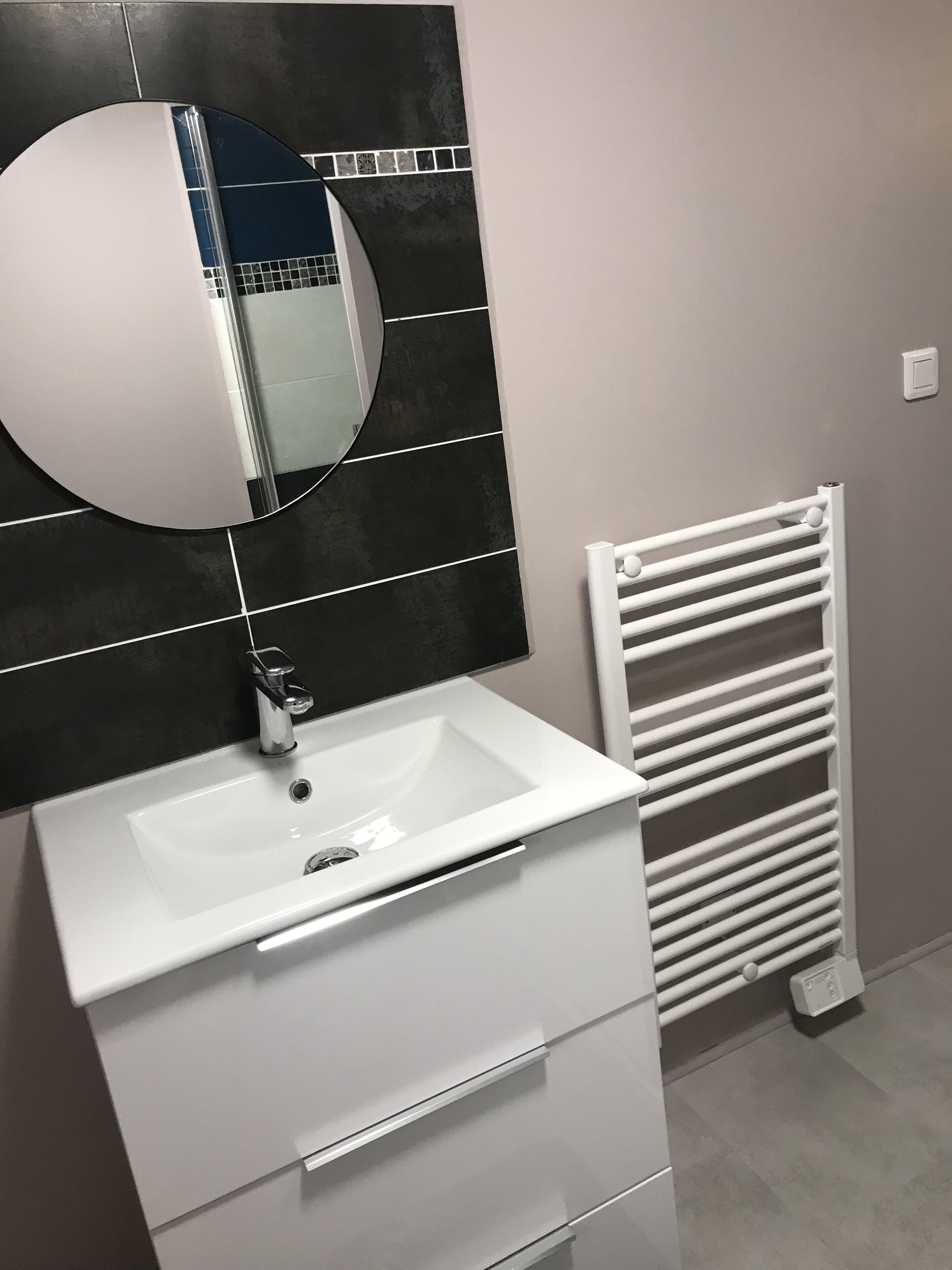A bathroom with a white sink, a mirror, and a white towel rack.