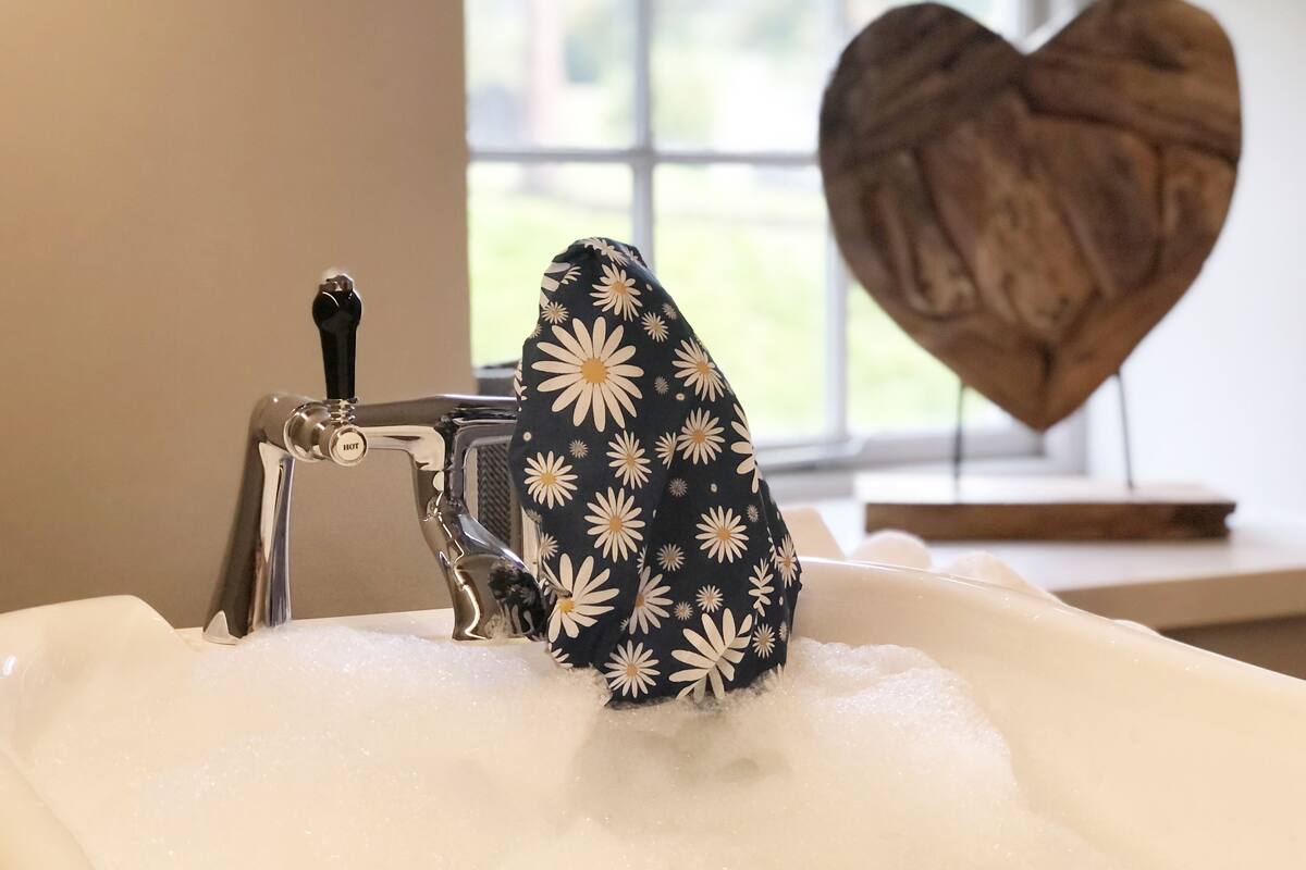 Un baño con una bañera llena de burbujas, un grifo y una decoración con forma de corazón en la pared.