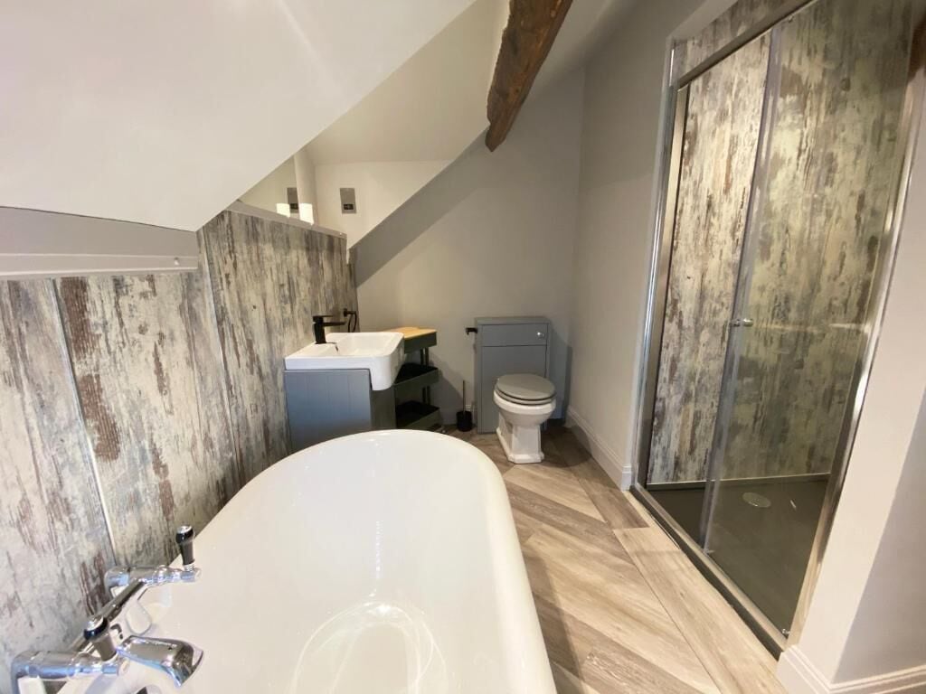 A bathroom with a bathtub, toilet, and shower area.