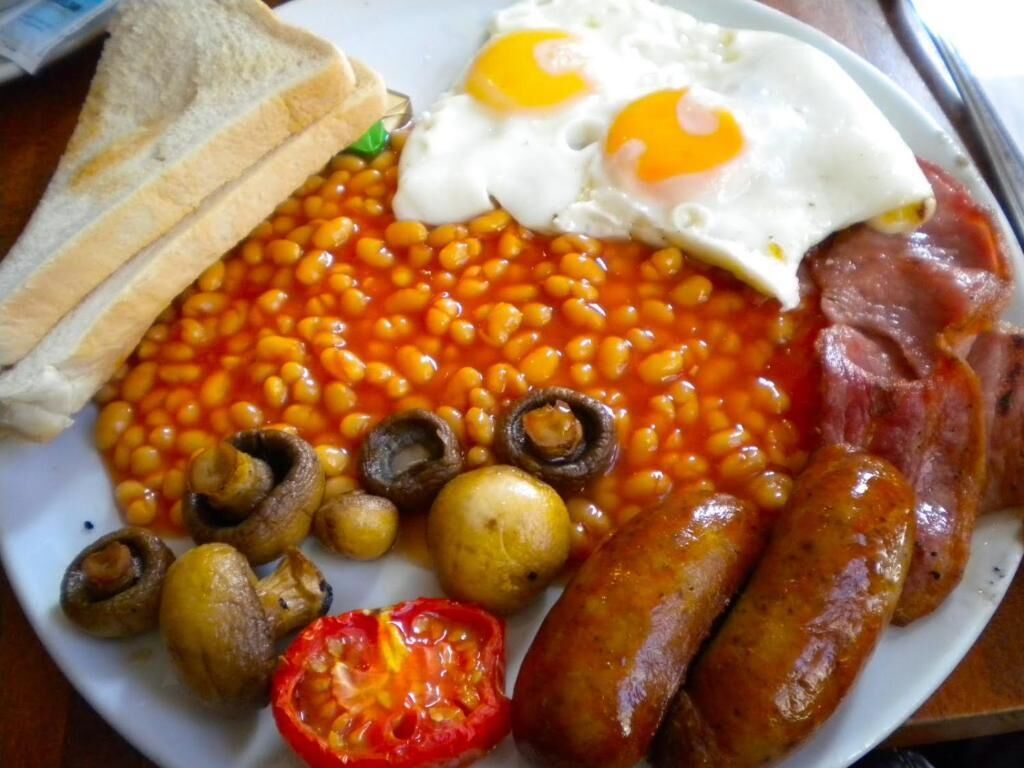 A plate with eggs, beans, sausages, mushrooms, and toast.